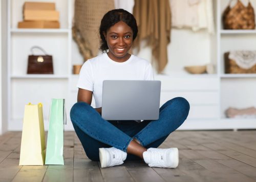 African Lady Shopping With Laptop Sitting Near Shopper Bags Indoor